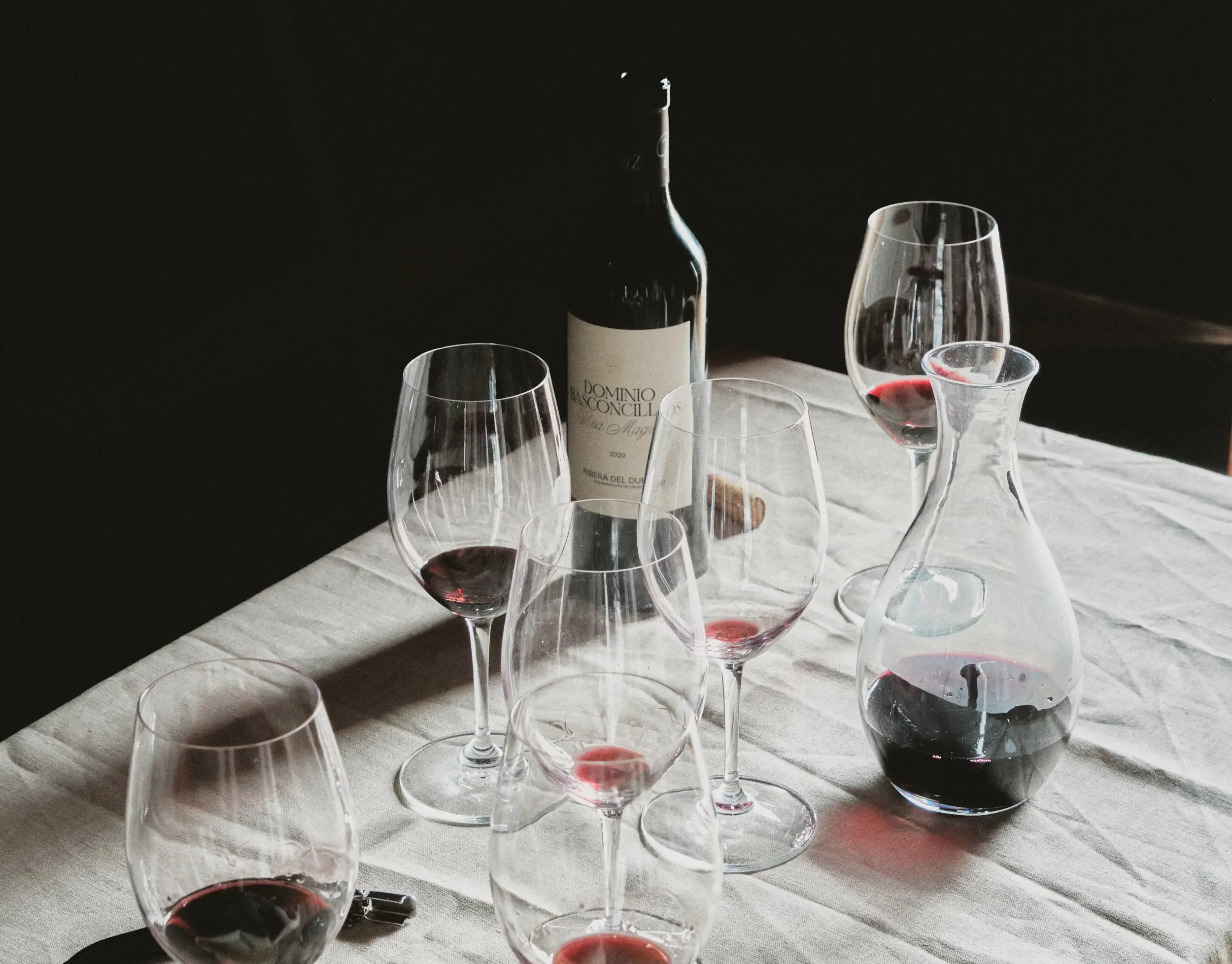 Arreglo de botella de vino tinto, copas y decantador sobre una mesa, invitando a una degustación.