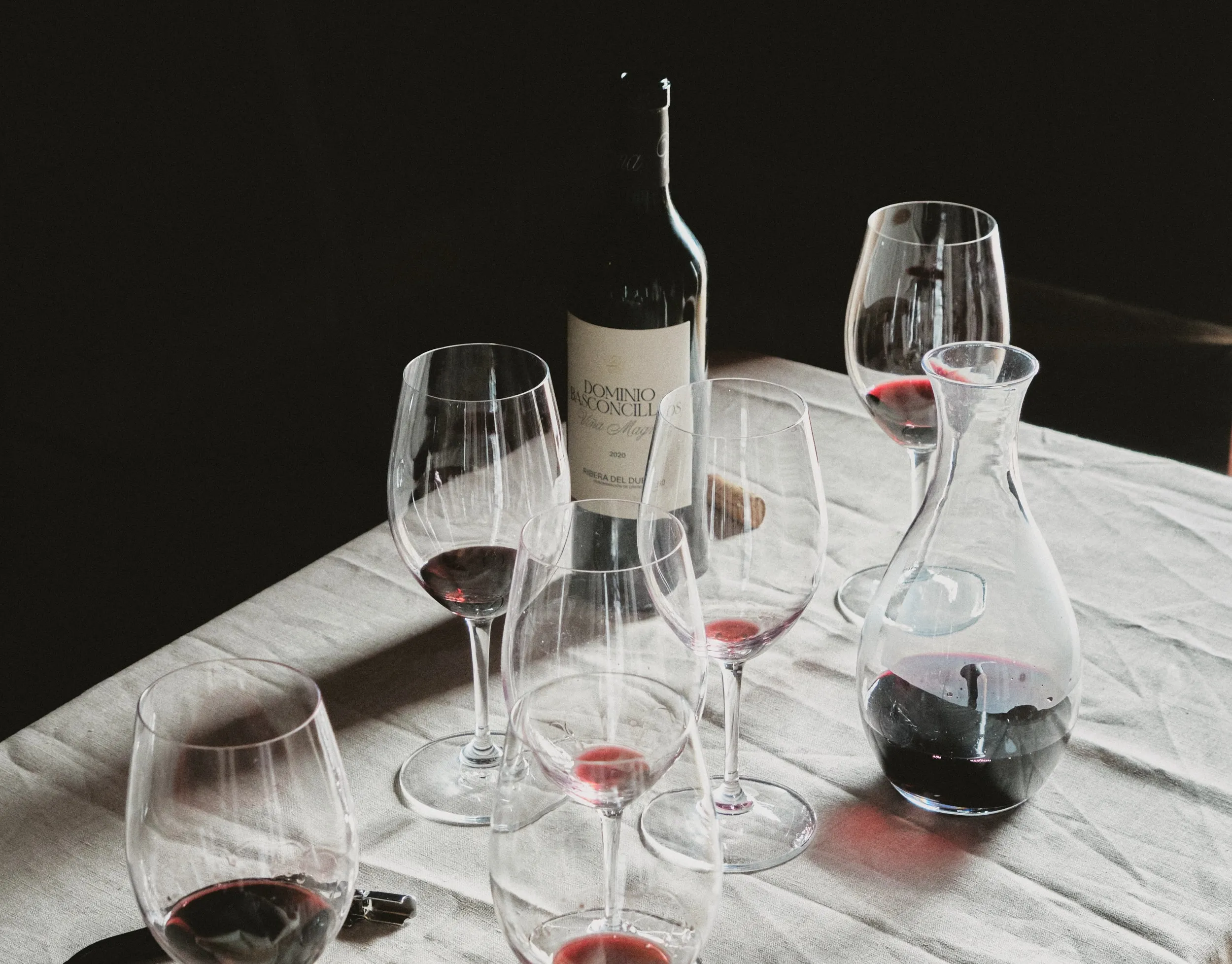 Arreglo de botella de vino tinto, copas y decantador sobre una mesa, invitando a una degustación.